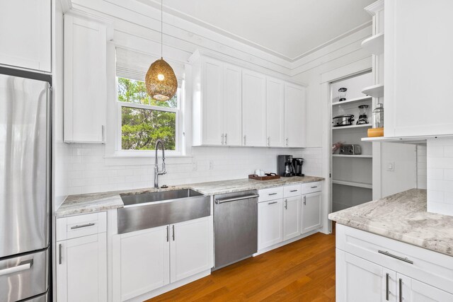 kitchen featuring appliances with stainless steel finishes, light hardwood / wood-style floors, sink, and backsplash