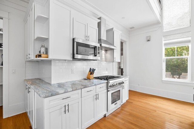 kitchen featuring backsplash, light hardwood / wood-style flooring, wall chimney exhaust hood, and gas range oven