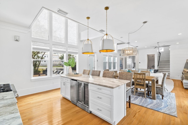 kitchen with light wood finished floors, visible vents, open floor plan, white cabinetry, and beverage cooler