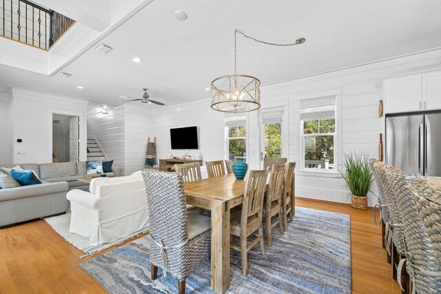 dining area featuring light hardwood / wood-style flooring and ceiling fan with notable chandelier