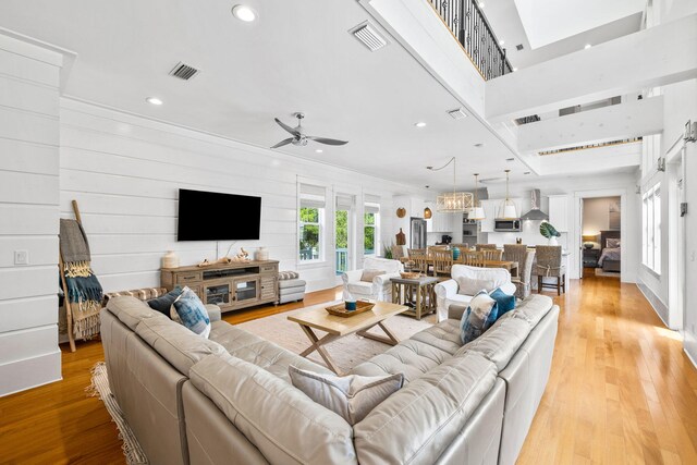 living room featuring light wood-type flooring, a high ceiling, and ceiling fan