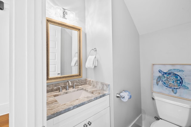 bathroom featuring lofted ceiling, vanity, and toilet