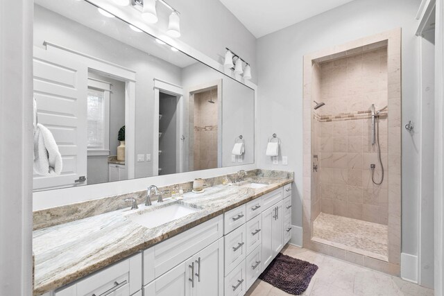 bathroom with tile patterned flooring, dual bowl vanity, and a tile shower