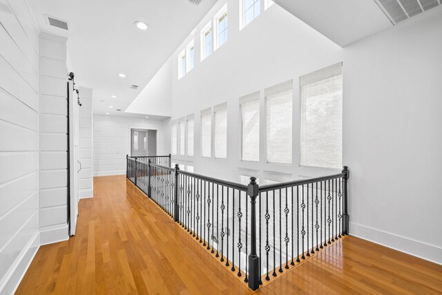 hall with a barn door, hardwood / wood-style flooring, and a towering ceiling