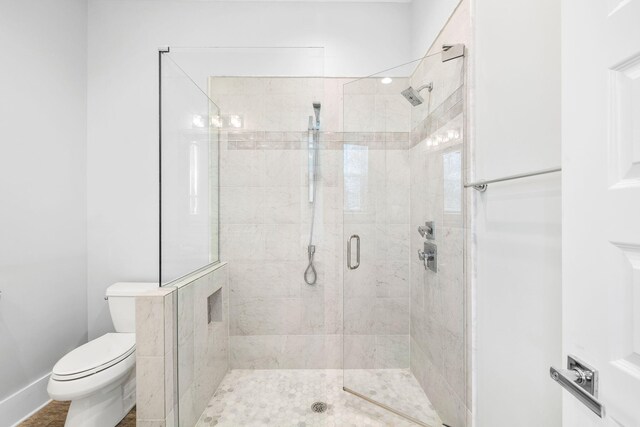 bathroom featuring toilet and a shower with shower door