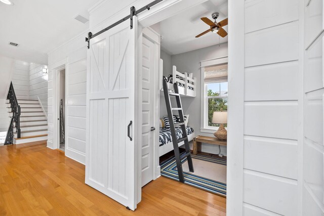 spacious closet with ceiling fan, light hardwood / wood-style flooring, and a barn door