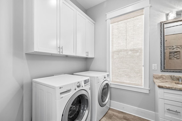 clothes washing area featuring cabinet space, baseboards, wood finished floors, and washing machine and clothes dryer