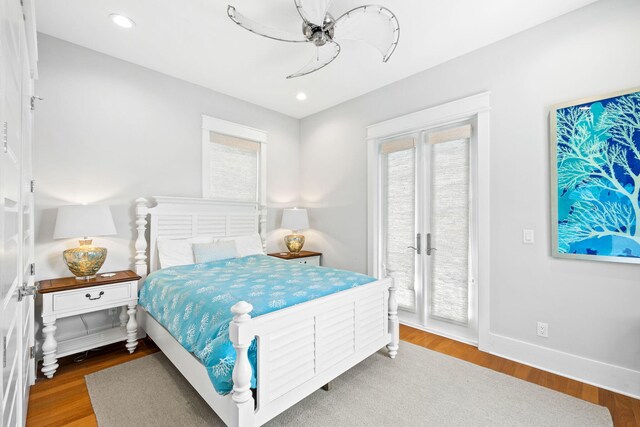 bedroom with ceiling fan, access to outside, hardwood / wood-style flooring, and multiple windows