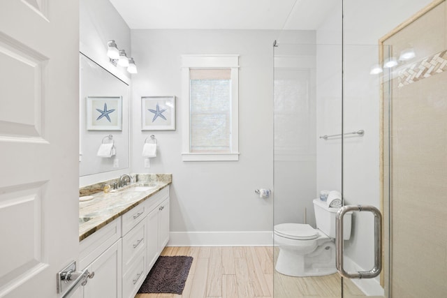 bathroom with a shower with door, double vanity, toilet, a sink, and baseboards