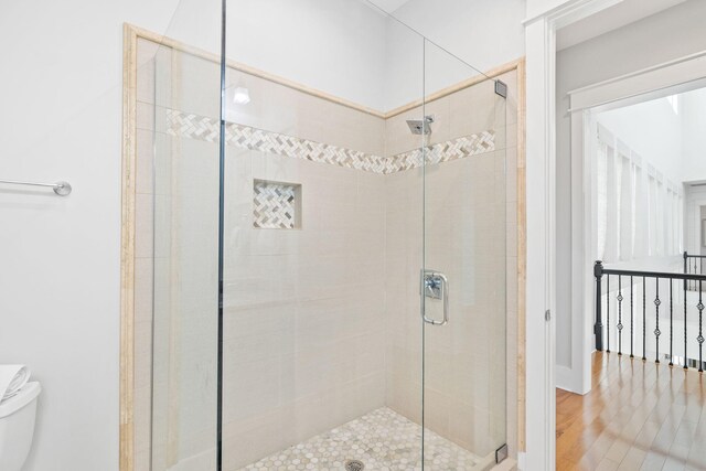 bathroom featuring hardwood / wood-style floors, walk in shower, and toilet