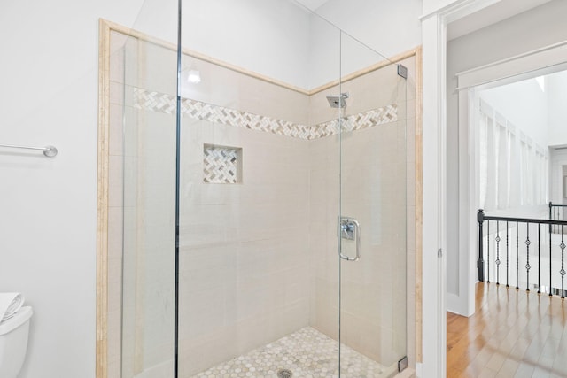 bathroom featuring wood finished floors, a shower stall, and toilet