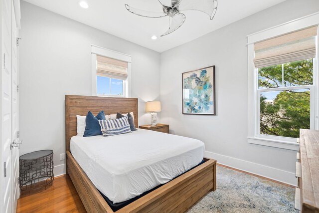 bedroom with ceiling fan, hardwood / wood-style floors, and multiple windows