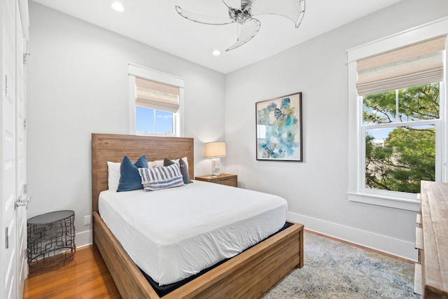 bedroom featuring multiple windows, baseboards, and wood finished floors