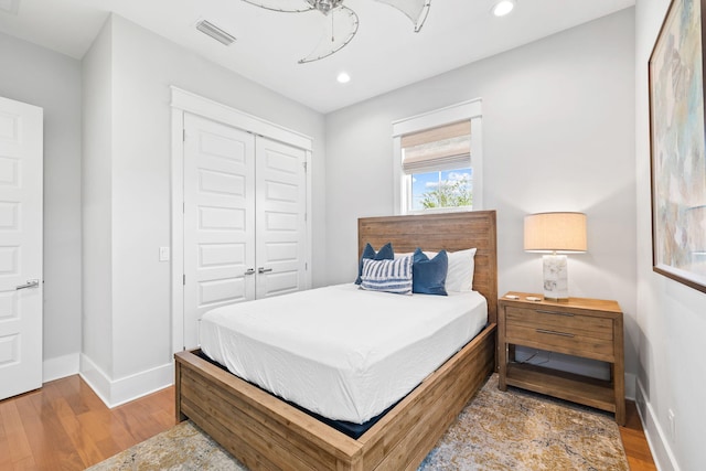 bedroom featuring a closet, wood finished floors, visible vents, and baseboards