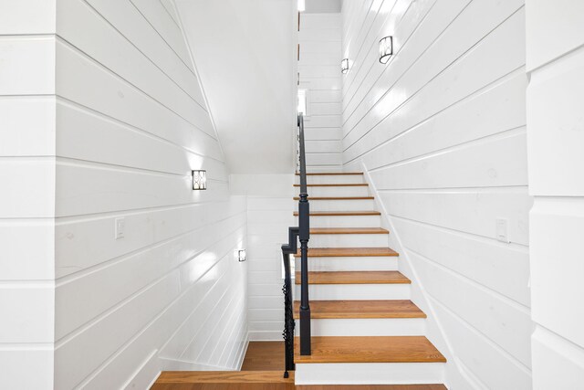 stairway with wood walls and wood-type flooring