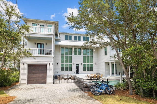 view of front of property with decorative driveway, french doors, fence, a balcony, and a garage