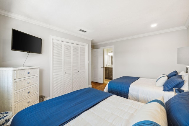 bedroom featuring hardwood / wood-style floors, crown molding, a closet, and ensuite bathroom