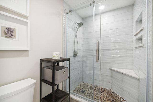 bathroom with a shower with door and toilet