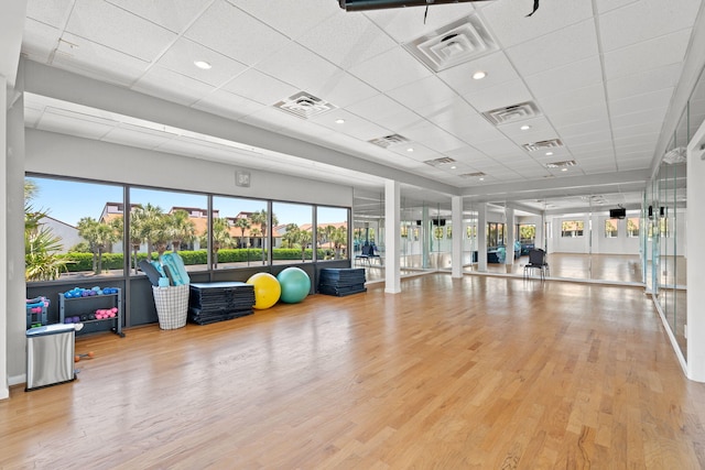 exercise room featuring a paneled ceiling, light hardwood / wood-style floors, and french doors