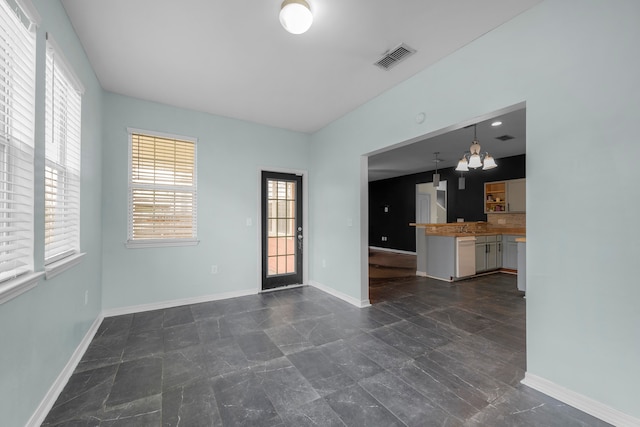 empty room featuring an inviting chandelier and a healthy amount of sunlight