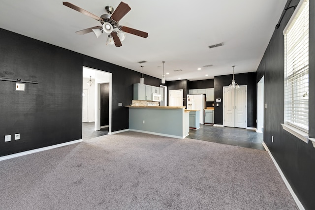 unfurnished living room featuring dark carpet and ceiling fan