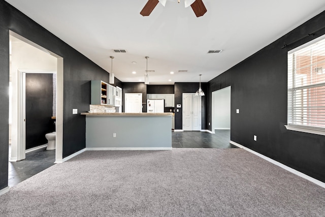 unfurnished living room with dark colored carpet and ceiling fan