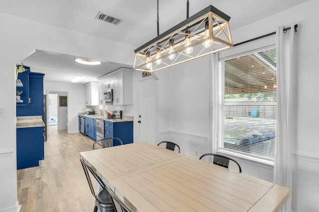 dining room with sink, light hardwood / wood-style flooring, and a chandelier