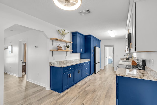 kitchen featuring sink, range, light hardwood / wood-style floors, blue cabinetry, and refrigerator