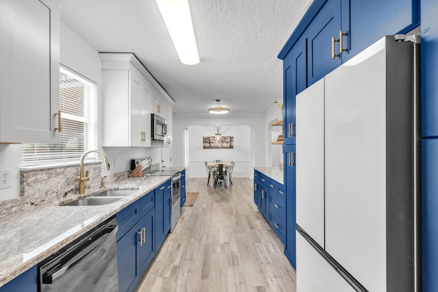 kitchen with blue cabinets, sink, light hardwood / wood-style flooring, white cabinetry, and stainless steel appliances