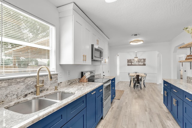 kitchen with blue cabinetry, white cabinetry, light hardwood / wood-style floors, sink, and stainless steel appliances