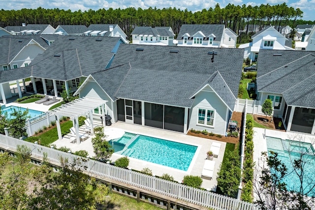 rear view of house featuring a fenced in pool, roof with shingles, a patio, a sunroom, and a fenced backyard