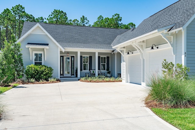 ranch-style home with a garage, concrete driveway, roof with shingles, and covered porch