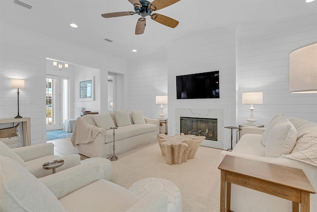 living room featuring ceiling fan, a fireplace, wood walls, and light wood-type flooring