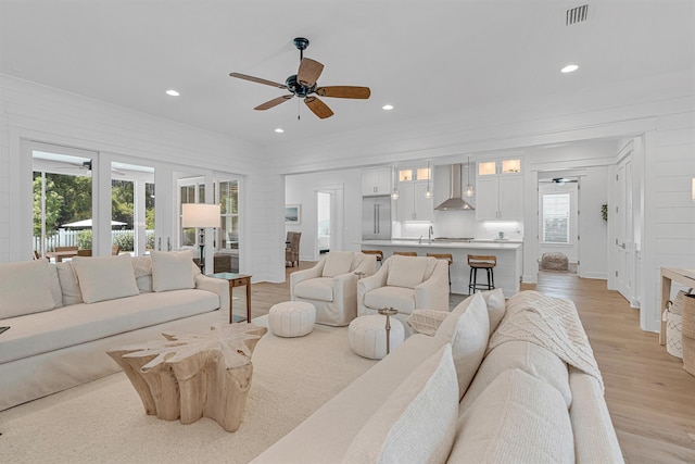 living room with light wood-type flooring, visible vents, a ceiling fan, and recessed lighting