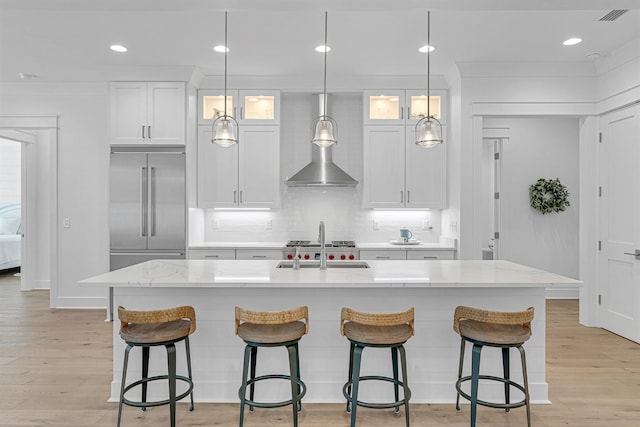 kitchen featuring stainless steel built in fridge, a kitchen island with sink, and white cabinets