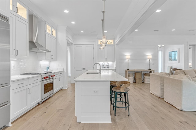 kitchen featuring wall chimney exhaust hood, designer stove, white cabinetry, and open floor plan