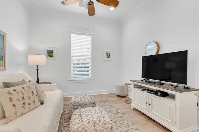 living room with light wood-type flooring, ceiling fan, ornamental molding, and baseboards