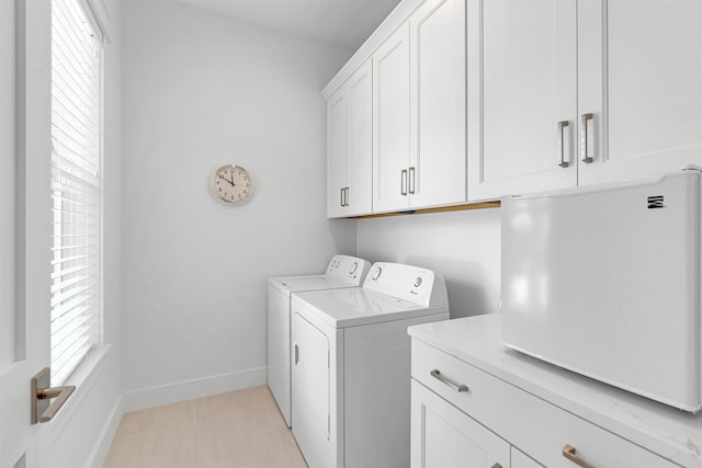 clothes washing area with washer and dryer, cabinet space, and baseboards