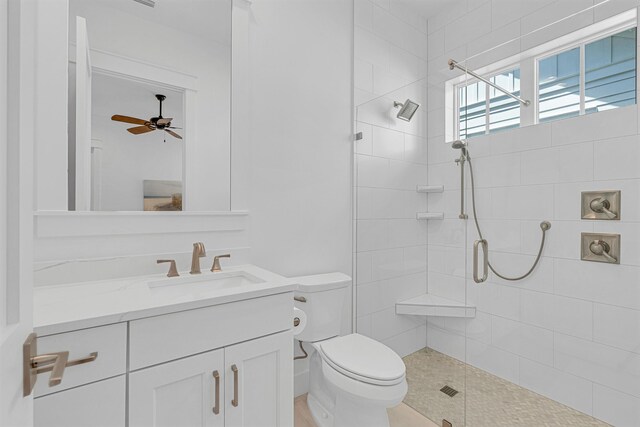 bathroom with a stall shower, vanity, toilet, and a ceiling fan