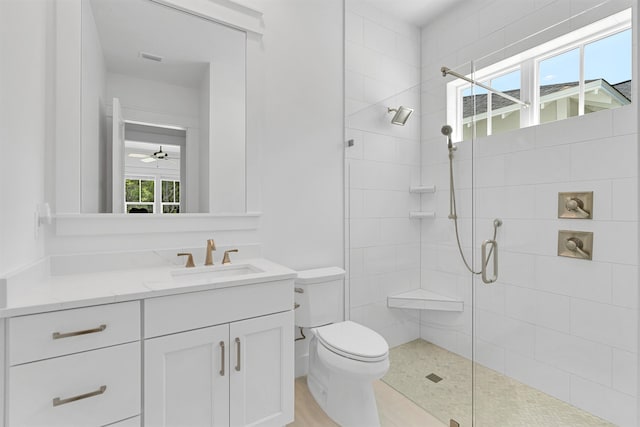 bathroom featuring ceiling fan, a shower with door, toilet, and vanity