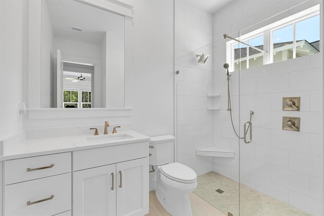 bathroom with toilet, plenty of natural light, tiled shower, and vanity