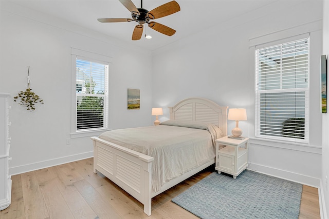 bedroom with light wood-type flooring, baseboards, a ceiling fan, and ornamental molding