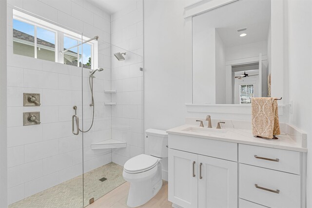 bathroom featuring ceiling fan, vanity, a healthy amount of sunlight, and toilet