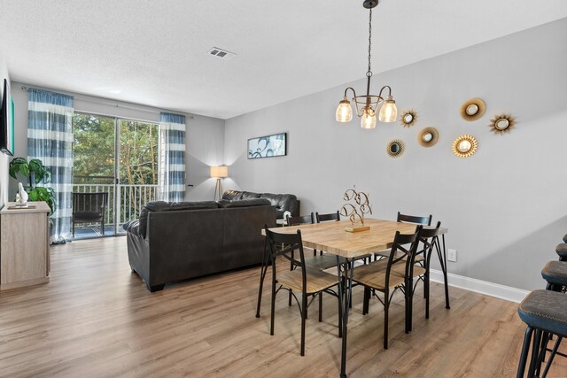 dining room featuring hardwood / wood-style flooring, a textured ceiling, and a chandelier