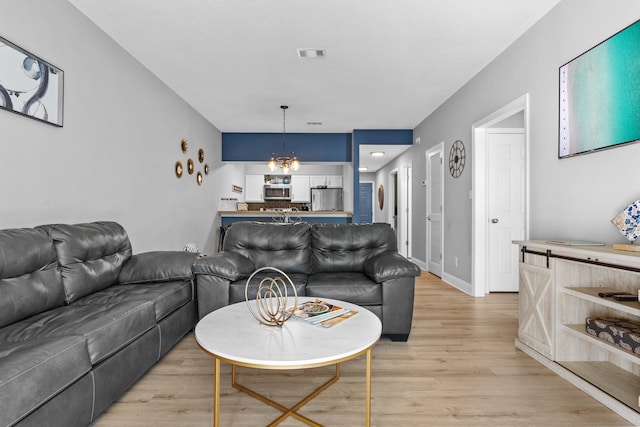 living room featuring a notable chandelier and light hardwood / wood-style flooring