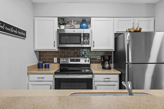 kitchen with decorative backsplash, white cabinetry, and stainless steel appliances