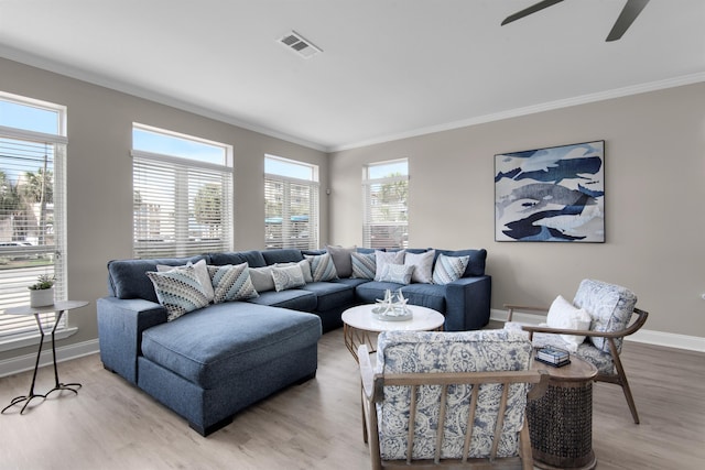 living room with ornamental molding, visible vents, light wood finished floors, and baseboards