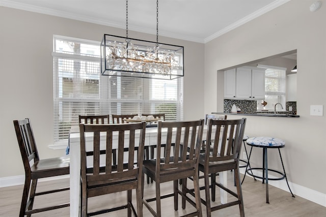 dining room featuring light wood finished floors, baseboards, a wealth of natural light, and crown molding