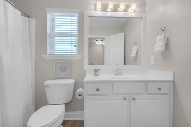 bathroom featuring baseboards, vanity, toilet, and wood finished floors