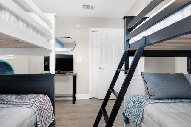 bedroom with wood finished floors, visible vents, and baseboards